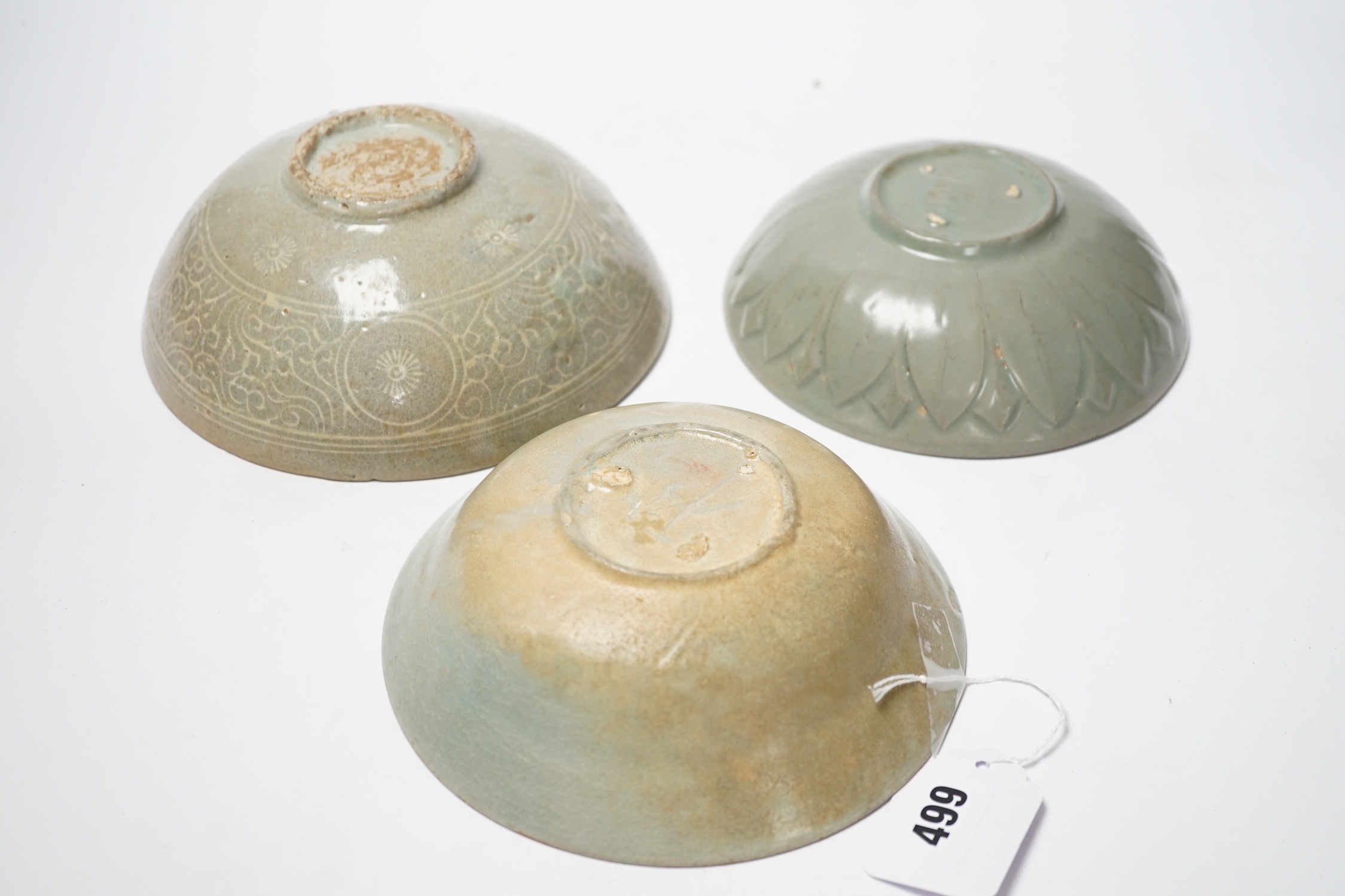 Two Korean celadon bowls, Goryeo dynasty (11th/12th century), the first carved with lotus petals to the underside, the second with fine crackle to the glaze, and a Korean slip-decorated celadon bowl (11th/12th century),